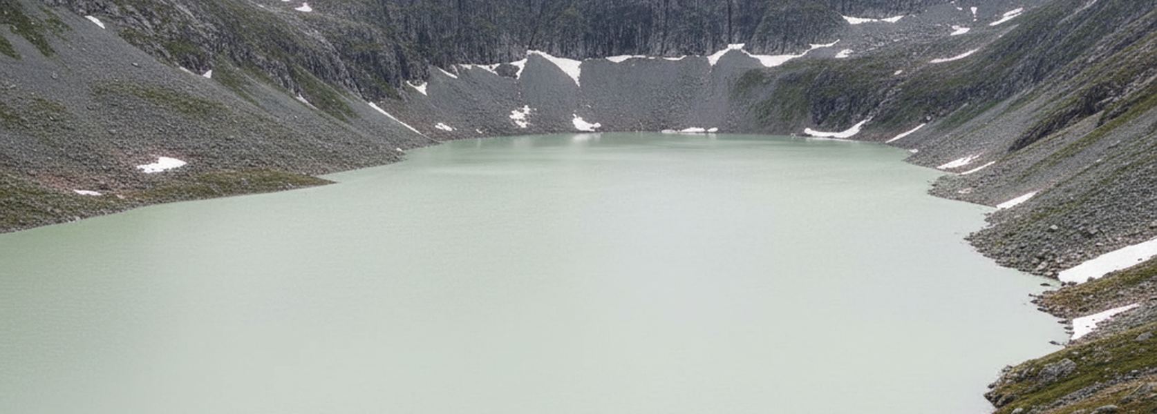A pale green glacial tarn filling a rock basin, gray scree flanks and old snow patches rising all round it.