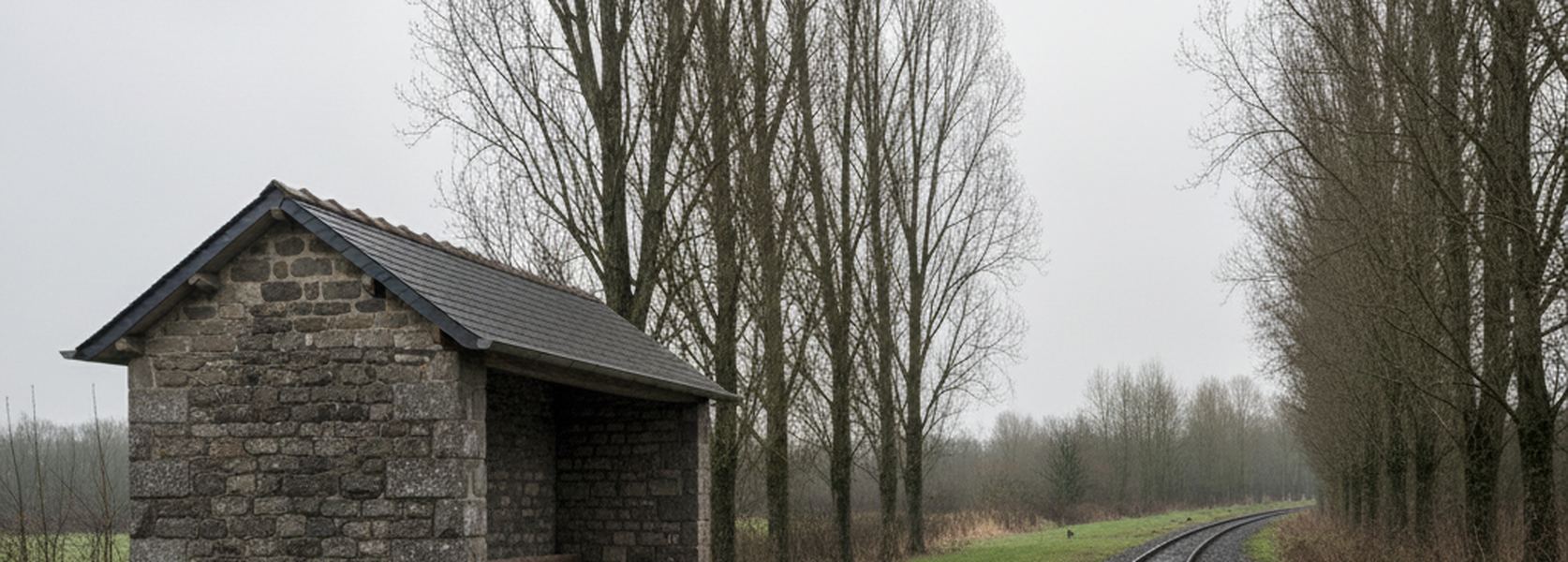 Two rails curve away between bare poplars past a small stone shelter with a dark open recess beside the empty track.